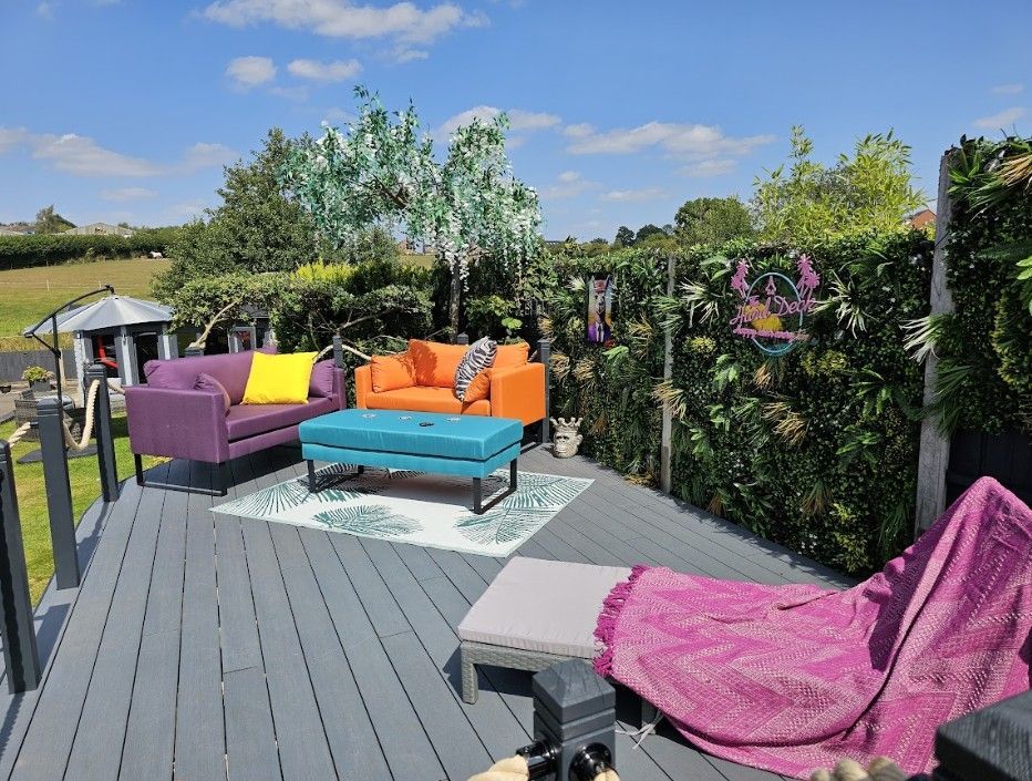 Lounge area on the finished Galley Common composite deck with outdoor sofas, green wall panels on the fence and open fields beyond