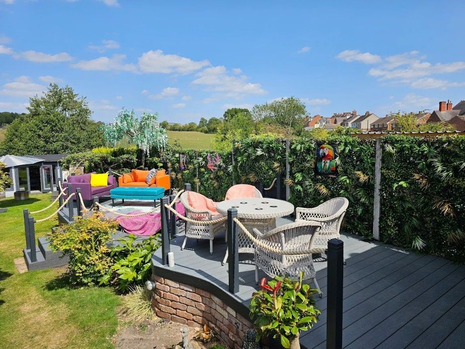 Finished composite deck built over the old pond in Galley Common, with the curved brick wall kept on show, rope balustrade and outdoor furniture
