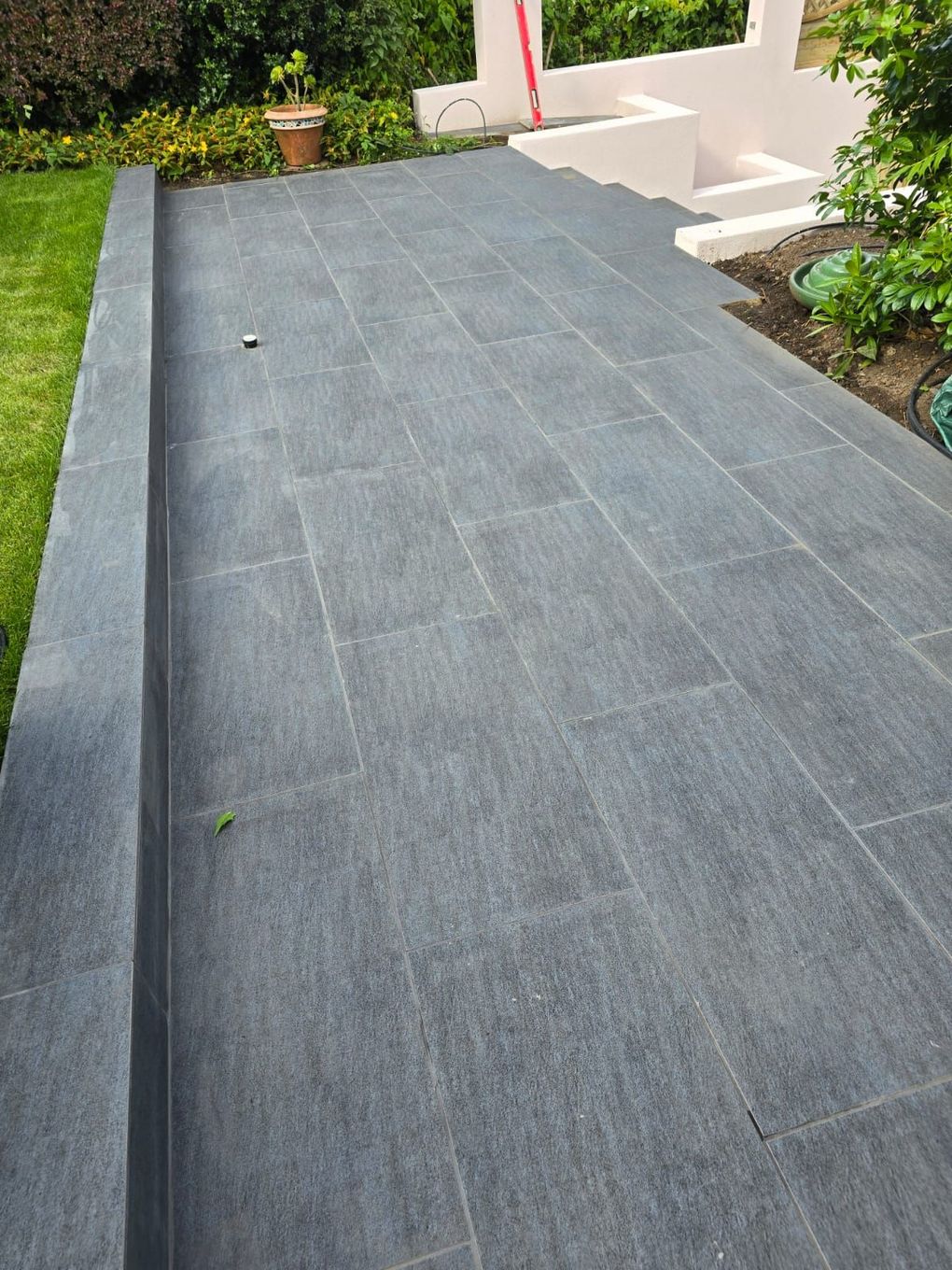 Finished dark porcelain path running beside the lawn in the tiered garden