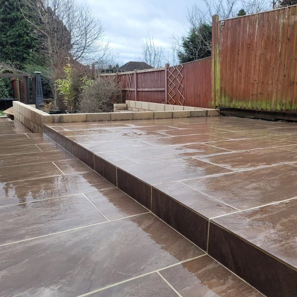 Warm-toned paving patio on two levels with a raised step and new block walls