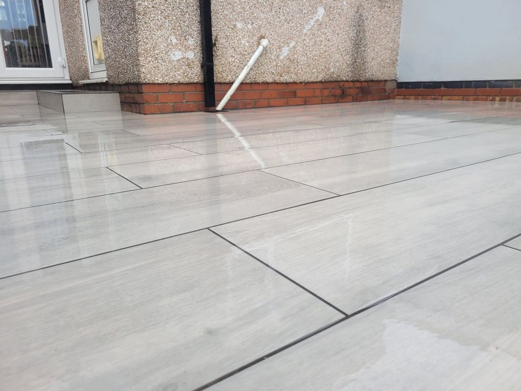 Close view of long light porcelain paving slabs with tight, straight joints outside a house