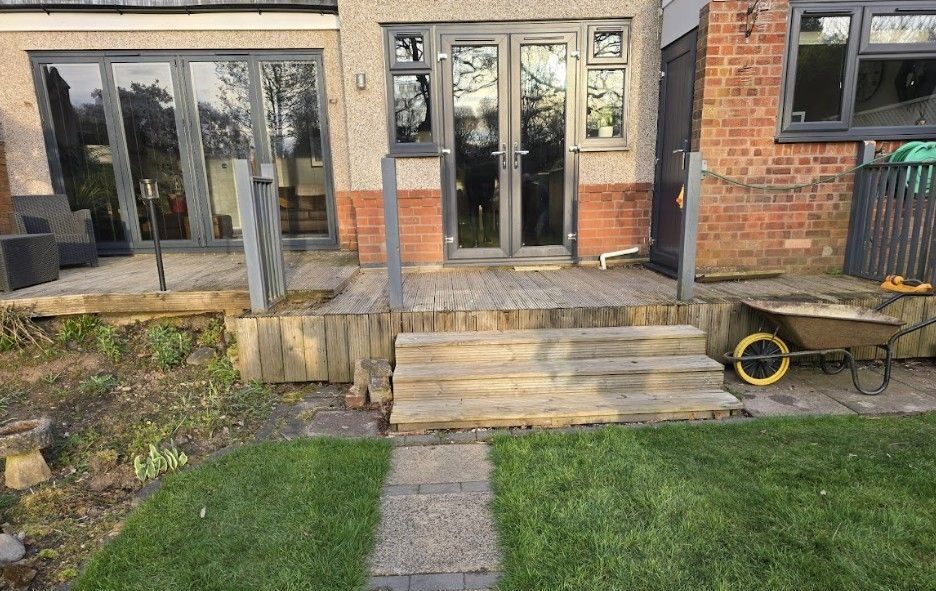 Earlsdon garden before landscaping, with tired raised timber decking, timber steps and a worn lawn behind the house