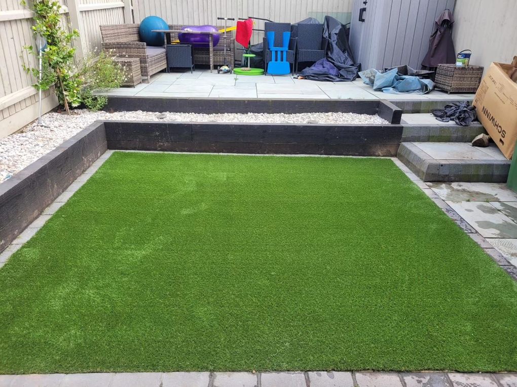 Artificial lawn framed by timber sleepers and paving below a raised patio