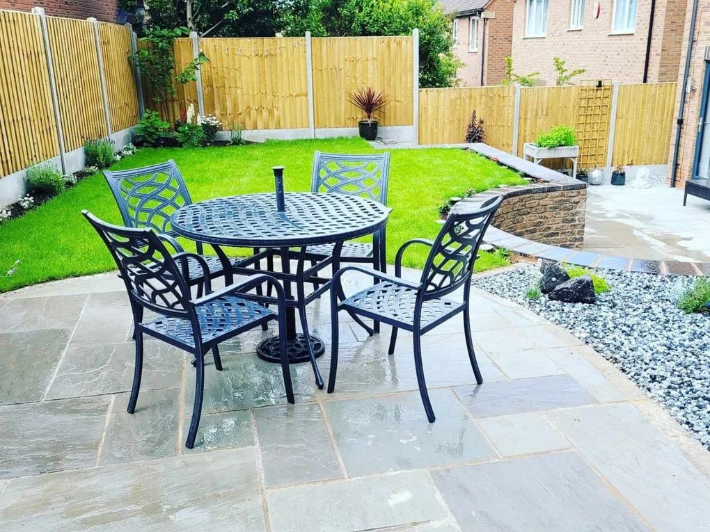 Sandstone patio and dining area beside a new lawn, with a curved retaining wall and slate gravel bed