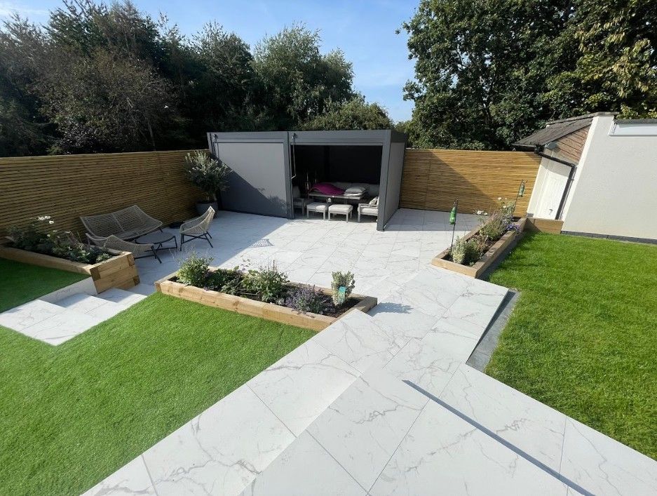 Finished Coundon garden with marble-effect porcelain terrace, sleeper raised beds, lawns and a dark grey pergola with outdoor seating
