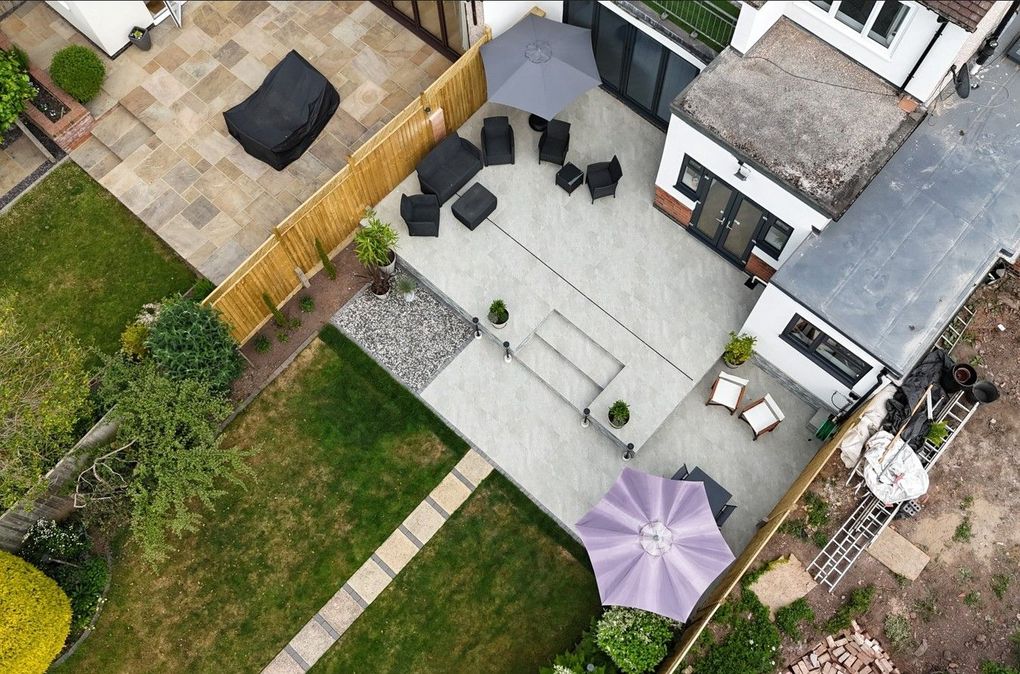 Drone view from above of the finished Earlsdon garden showing the two-level light grey porcelain terrace, steps and gravel border