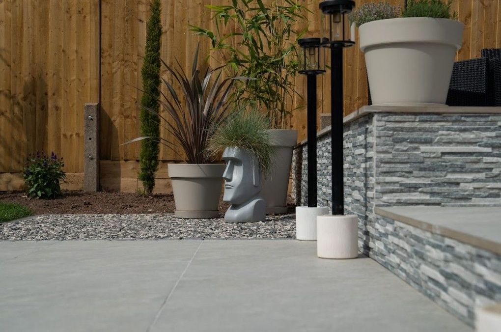 Planters and ornaments against new fencing beside the stone-clad terrace wall in the finished Earlsdon garden