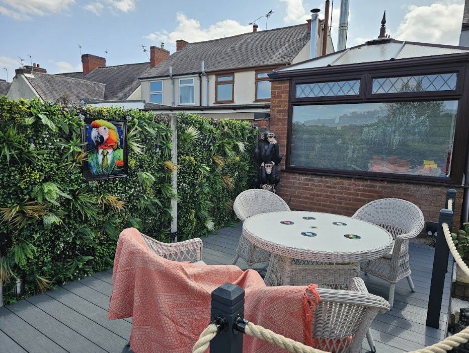 Composite deck with dining furniture, rope balustrade and green wall panels in front of a house in Galley Common, Nuneaton