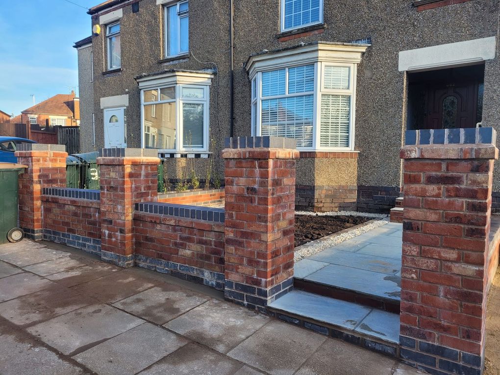 Red brick front garden walls with brick piers, blue brick capping and stone steps up to the front door