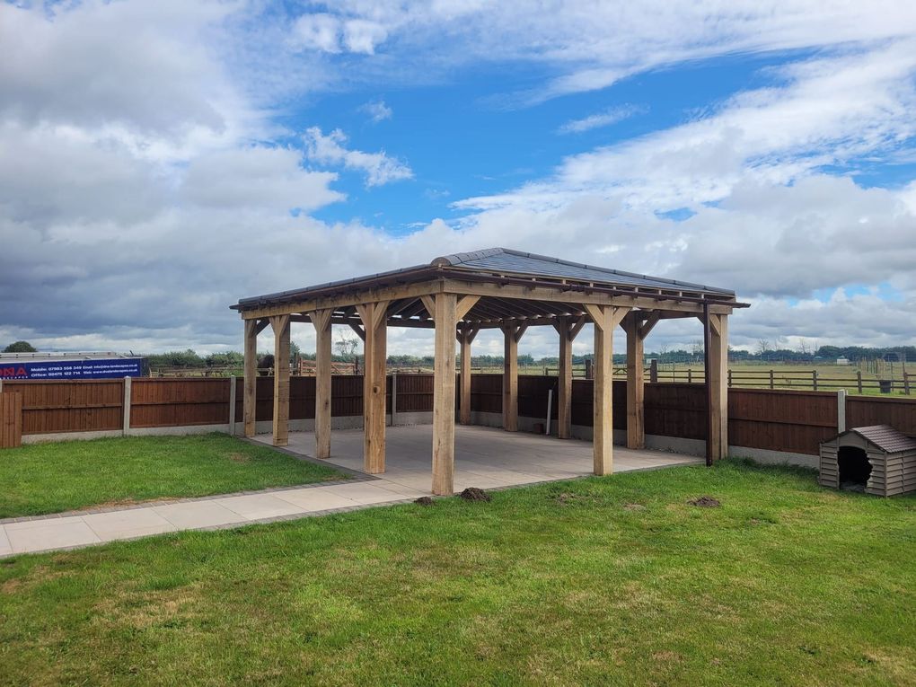 Large timber gazebo on a lawn with open fields beyond