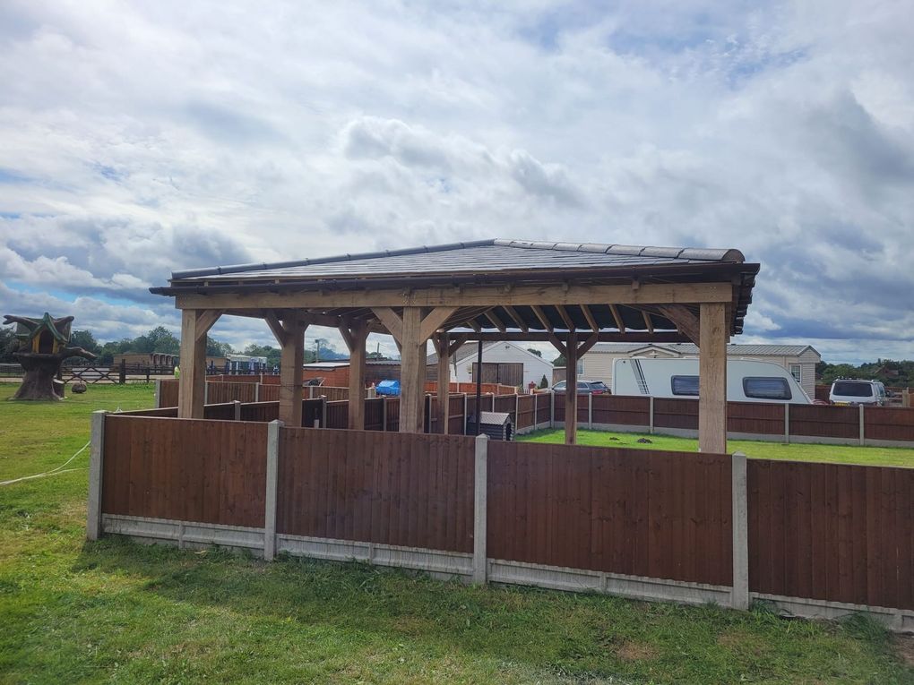 Timber gazebo with a tiled roof seen over a new closeboard fence