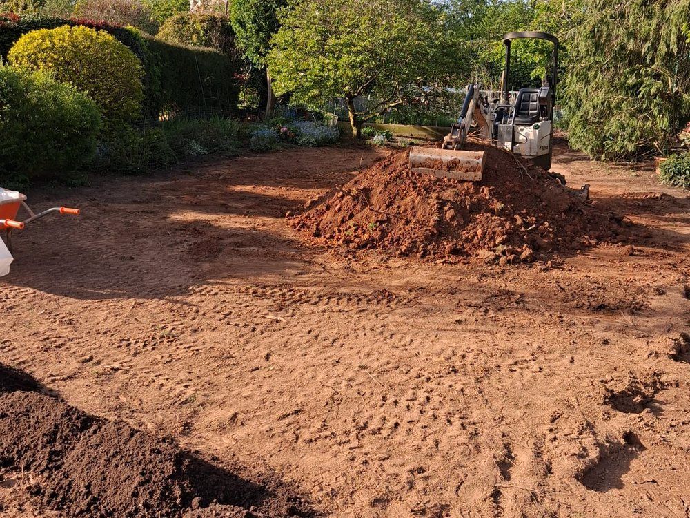 Garden stripped back to red clay subsoil with excavated spoil heaped ready for removal during a drainage job