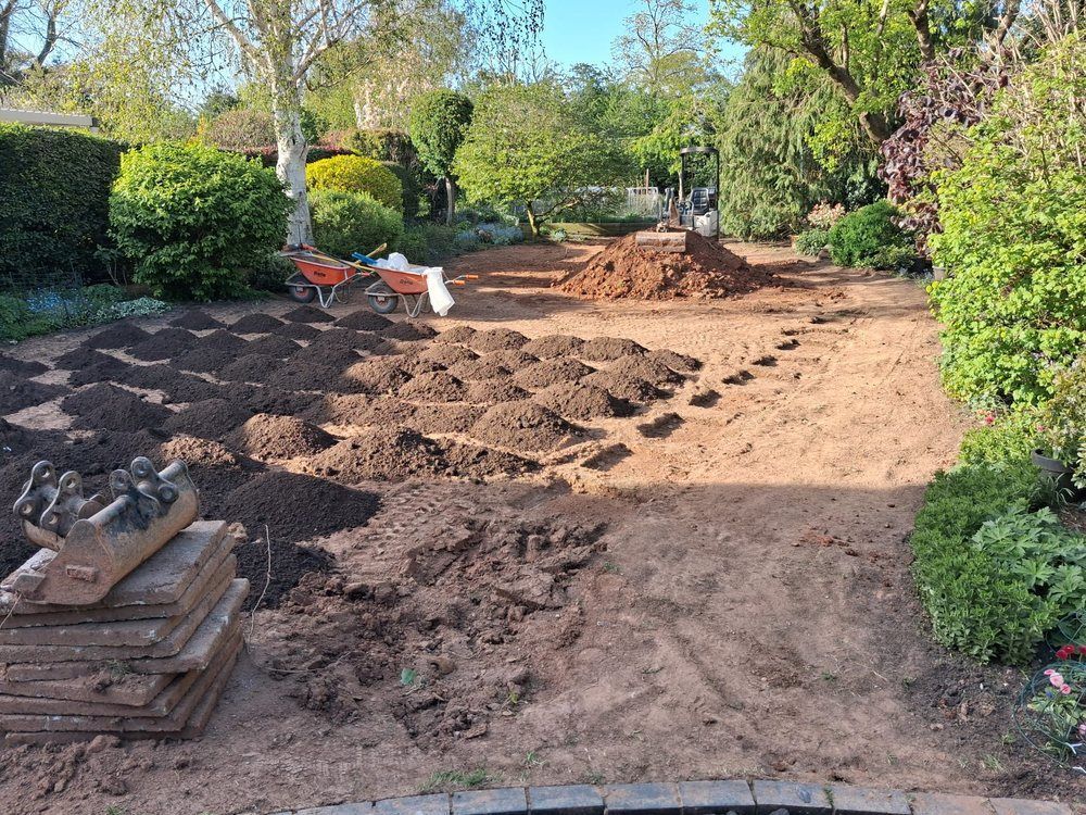 Drainage trenches set out across a large garden with spoil and boards during excavation