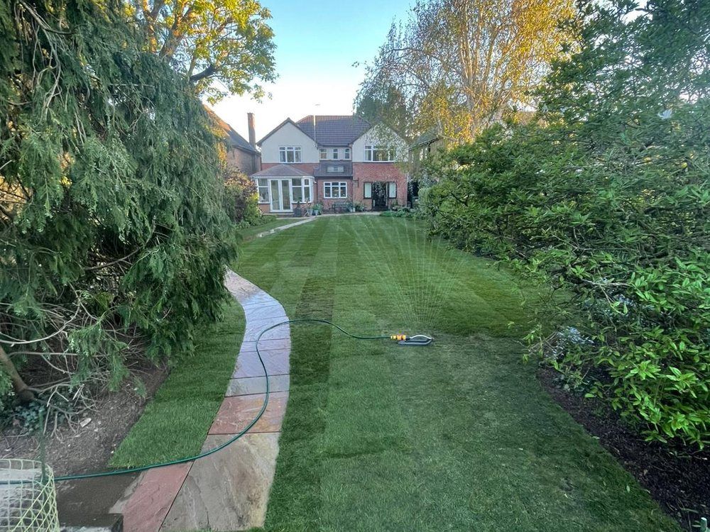 New lawn and curving stone path in a large garden after drainage work was completed