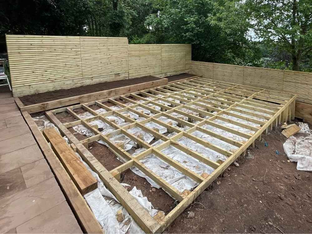 Completed timber deck joist framework on membrane with new slatted fencing and sleeper planting bed behind