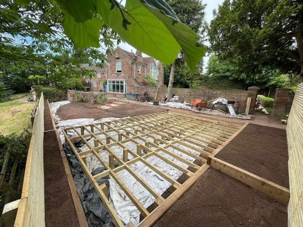 Timber deck subframe under construction with the Grade II listed sandstone house and original boundary wall behind