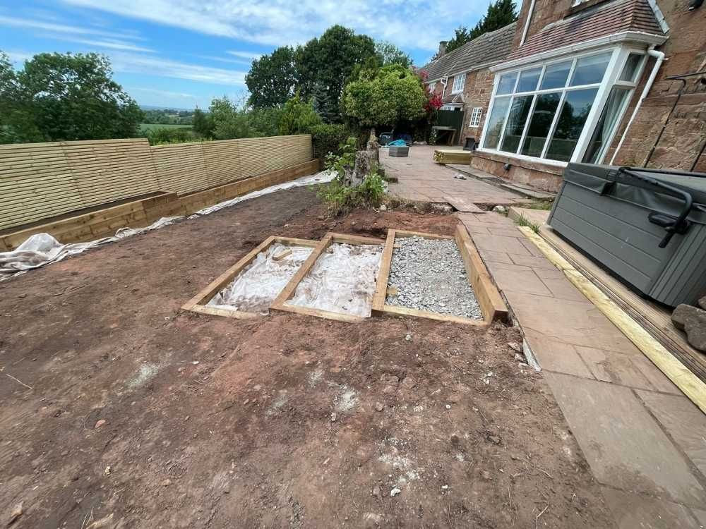 Excavated garden with timber frame bases and membrane beside an existing sandstone patio at Quarry House
