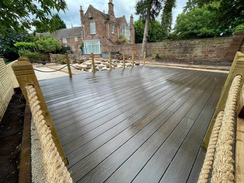 Walnut composite deck with rope balustrade looking towards the Grade II listed sandstone property and original wall