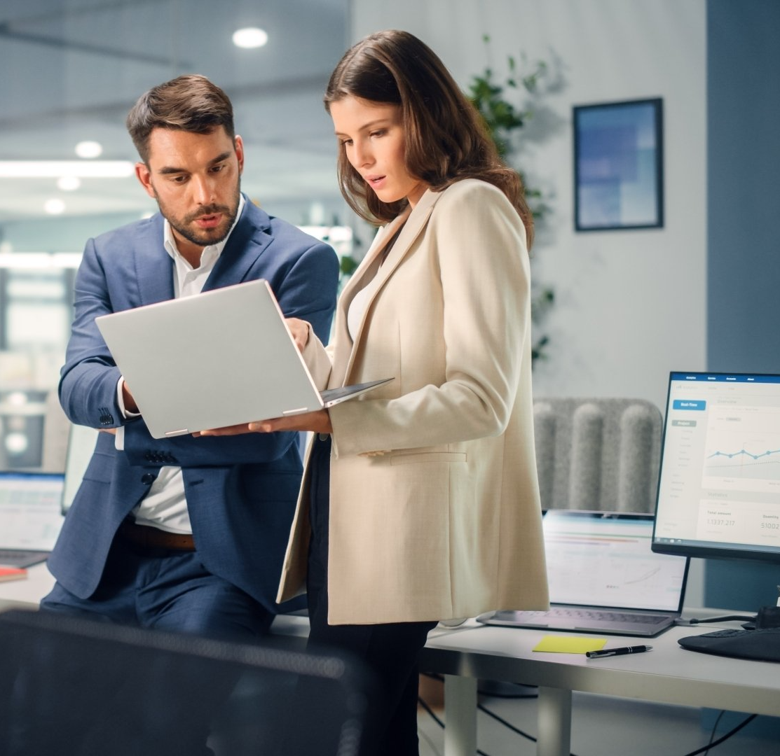 A man and a woman are looking at a laptop computer