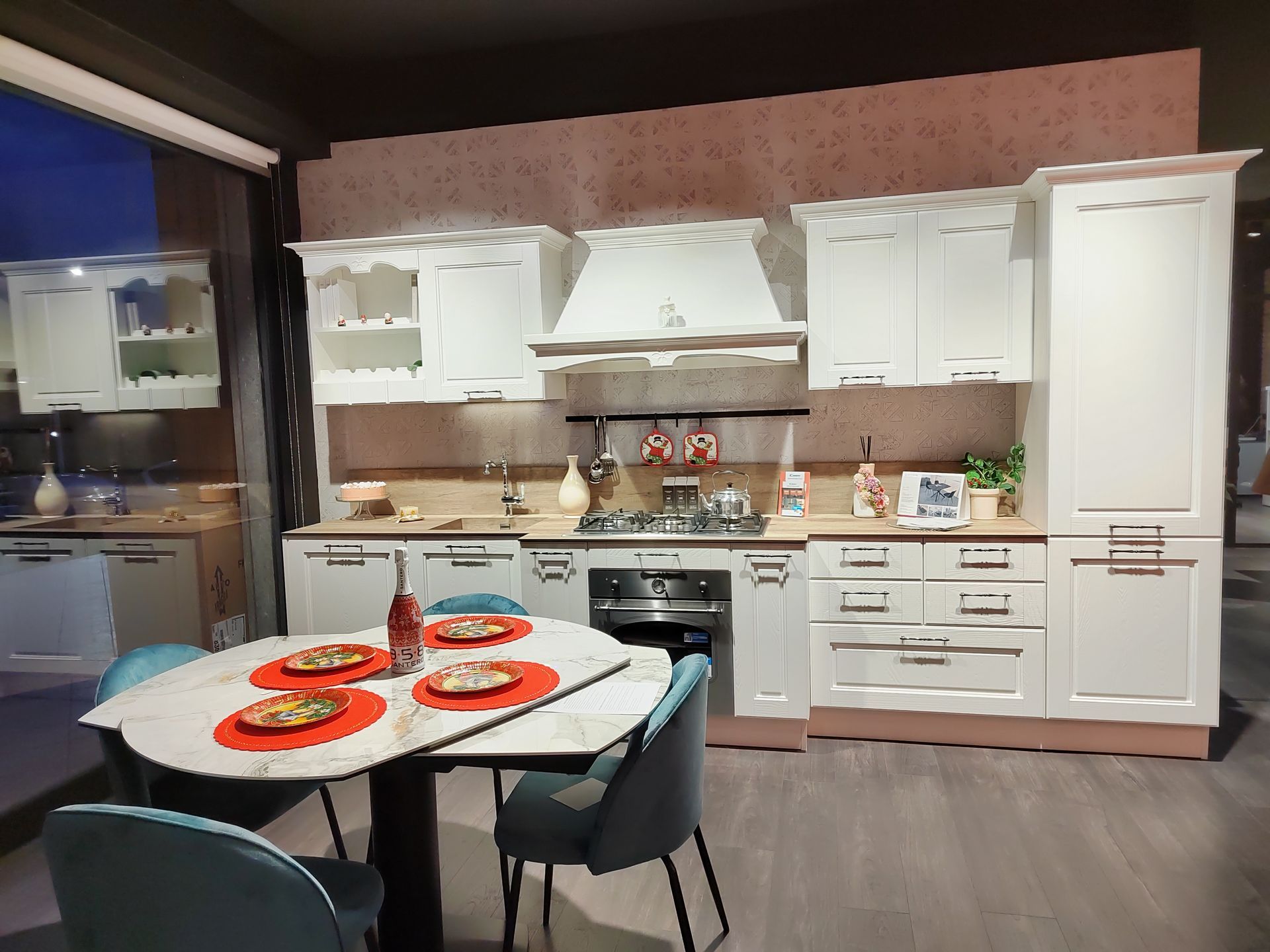 Mobili da cucina bianchi con tavolo da pranzo ovale e sedie blu.