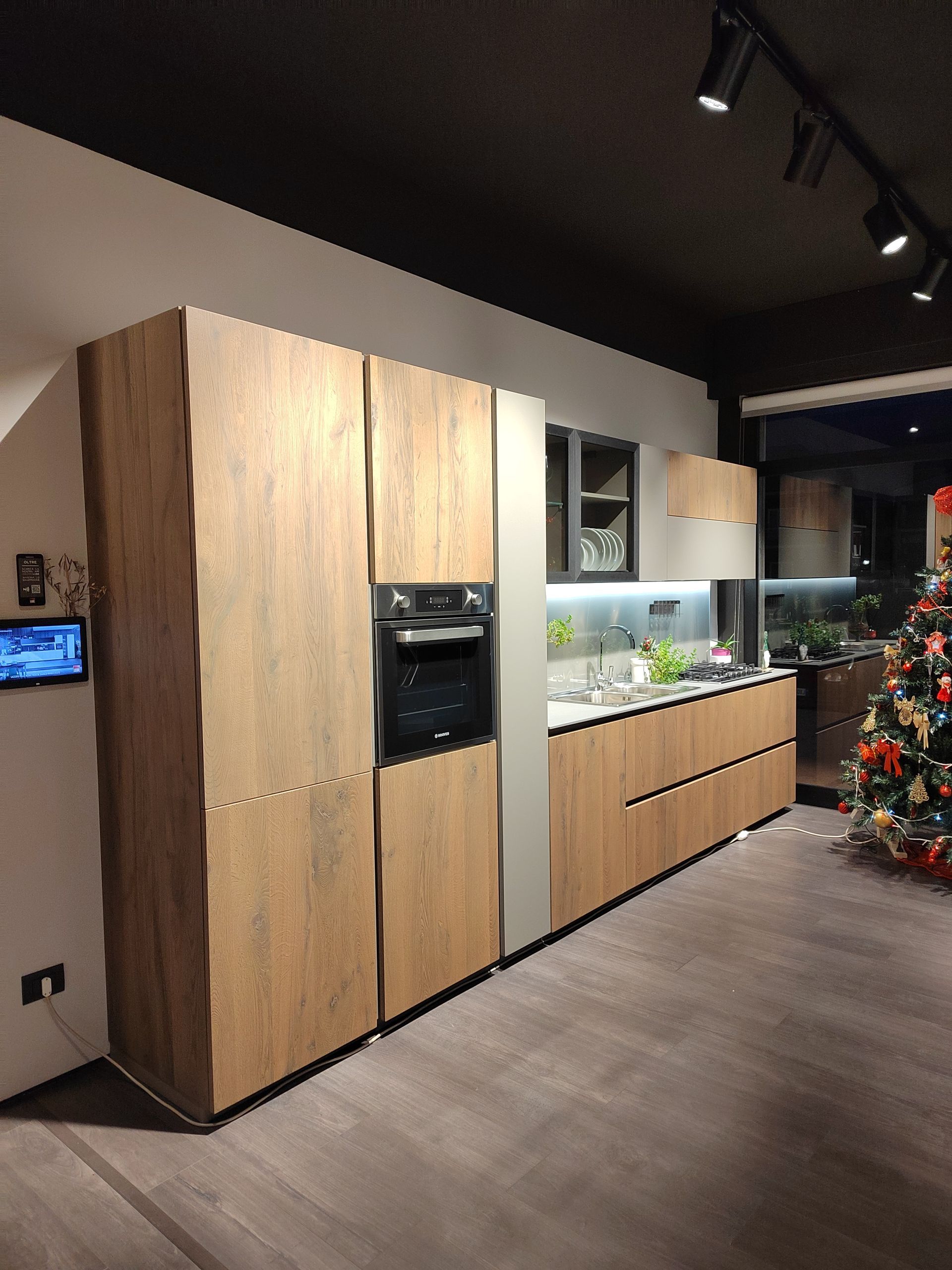 Cucina moderna con mobili in legno, forno incorporato e dettagli in acciaio inossidabile.