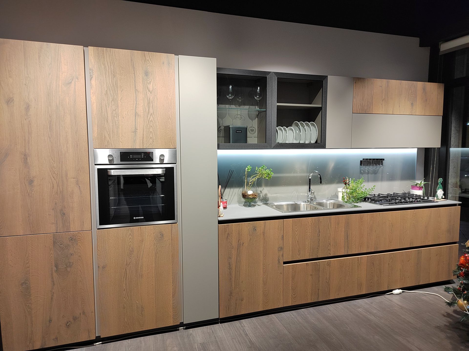 Cucina moderna con mobili in legno, elettrodomestici in acciaio inossidabile e paraschizzi grigio.