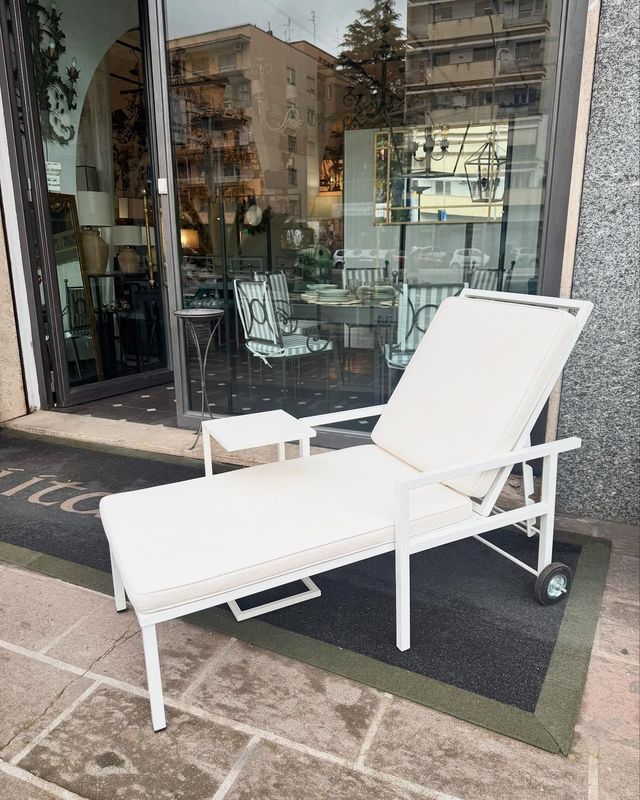 Poltrona bianca su un patio antistante un edificio con facciata in vetro.