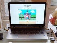Laptop screen displaying a schoolhouse illustration with a 
