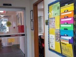 Hallway with automatic door on left, bulletin board on right, office visible.
