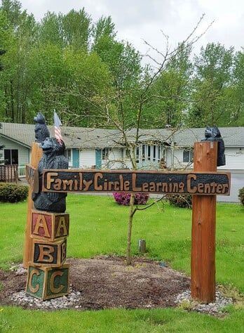 Sign for Family Circle Learning Center with wooden bear carvings and alphabet blocks.