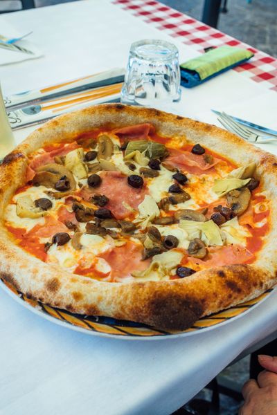 Pizza con pesto, prosciutto e basilico. La crosta è dorata e gonfia.