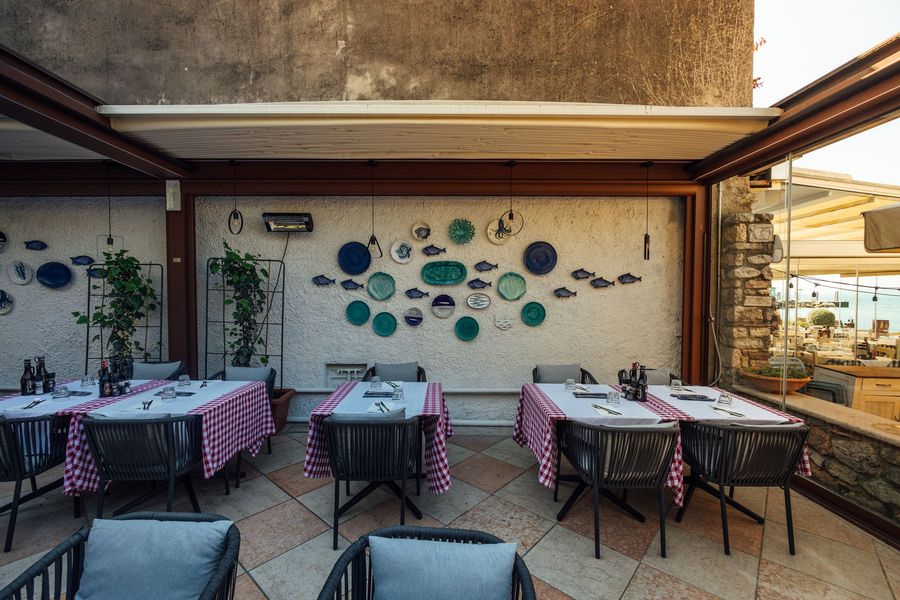 Tavolo da pranzo all'aperto apparecchiato per gli ospiti, circondato dal verde e da lucine.