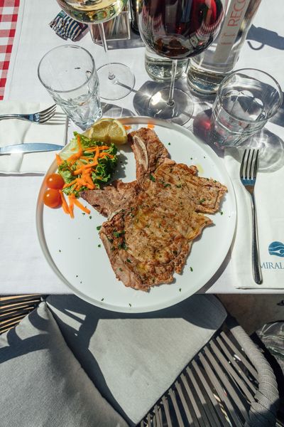 Piatto di frutti di mare con gamberi, capesante, pesce e verdure su un piatto decorativo, con limone.