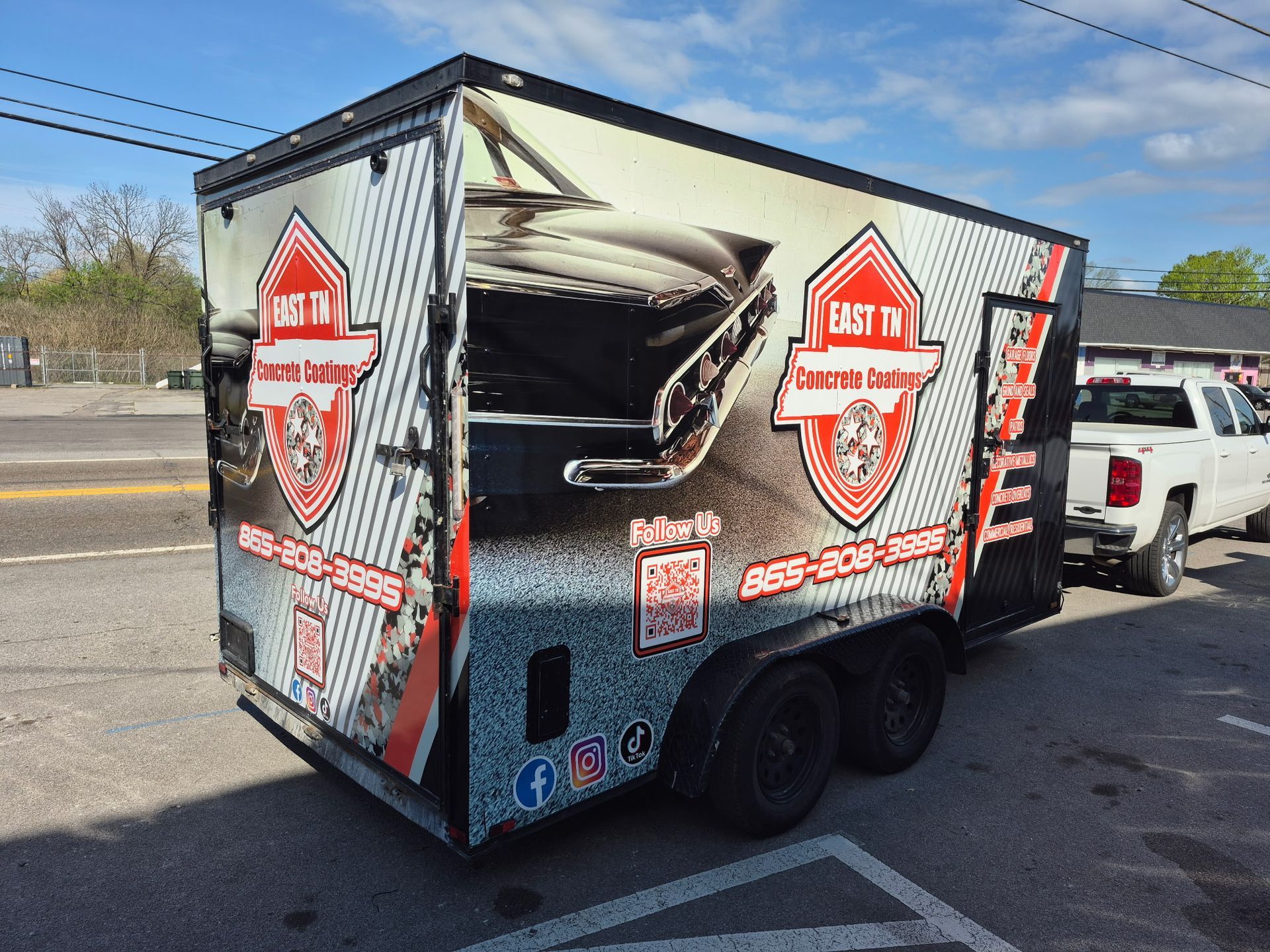 Black  trailer with red logos and grill graphic parked on a street