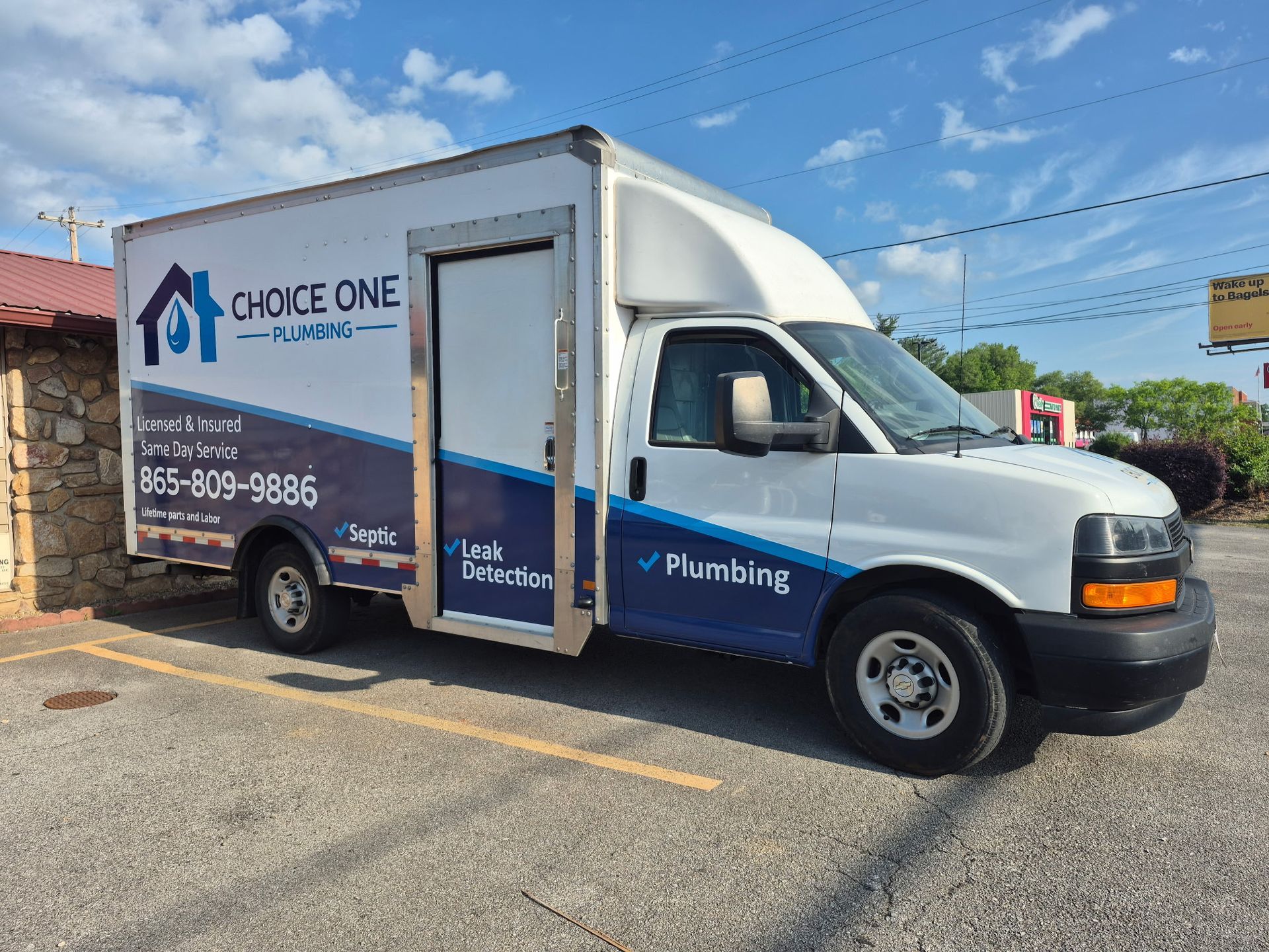 White Choice One Plumbing service van parked on a street, with side door open and company logo visible.