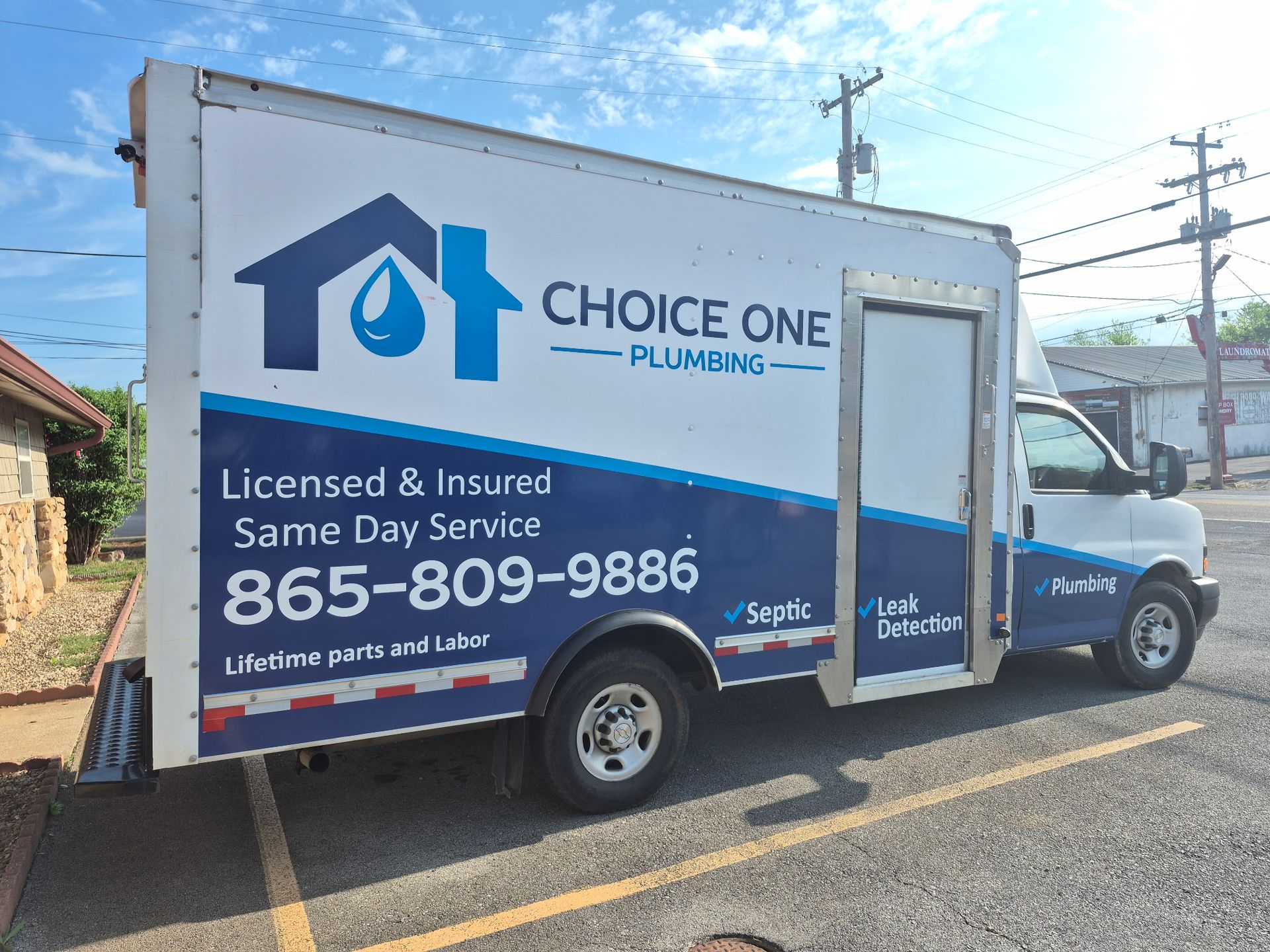 Blue Choice One Plumbing service truck parked on a street, with phone number and logo on the side.