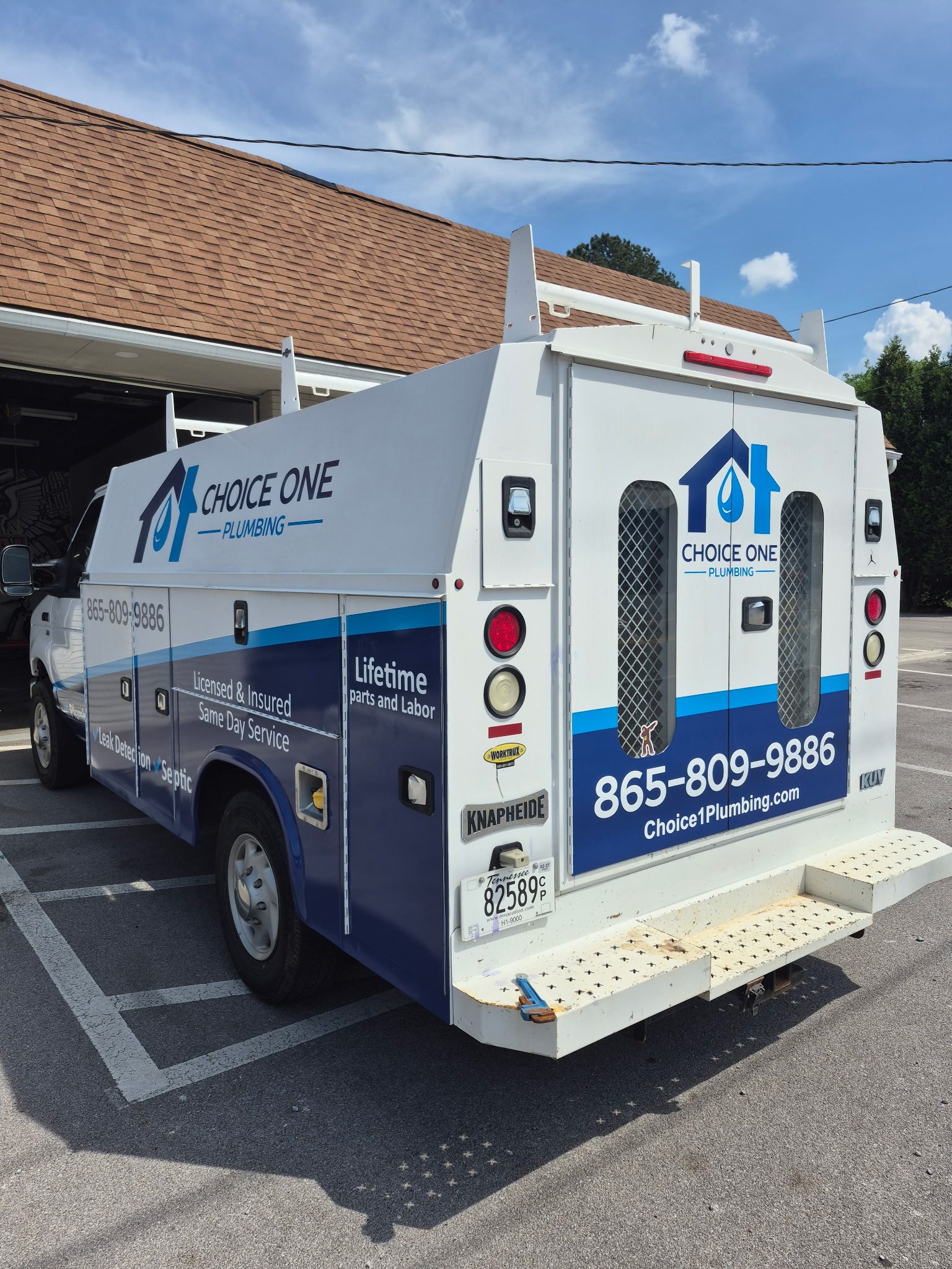 White medical transport van with wheelchair-access logo parked outside a building under a blue sky