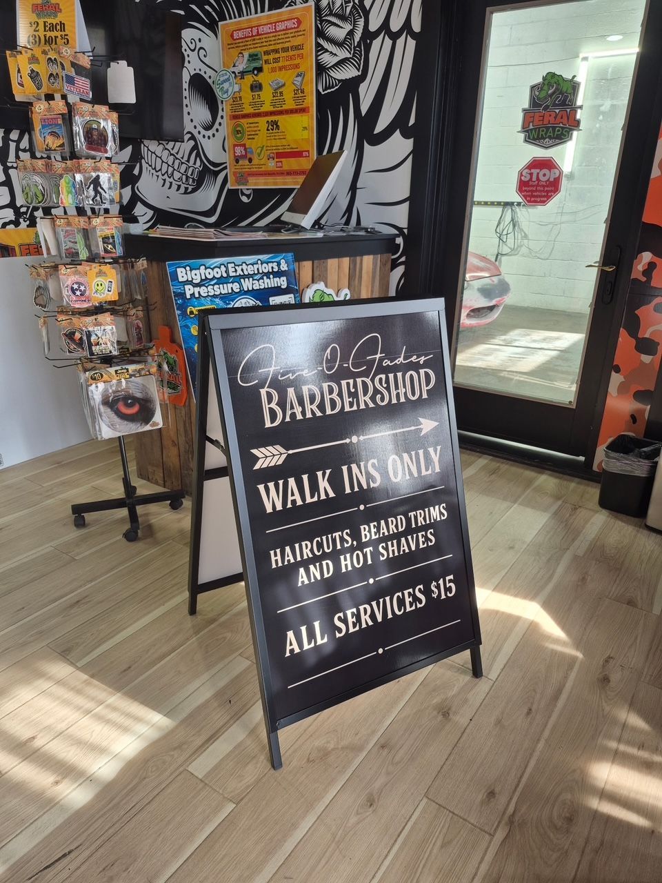 Barbershop sidewalk sign advertising walk-ins, haircuts, beard trims, and all services in a storefront window