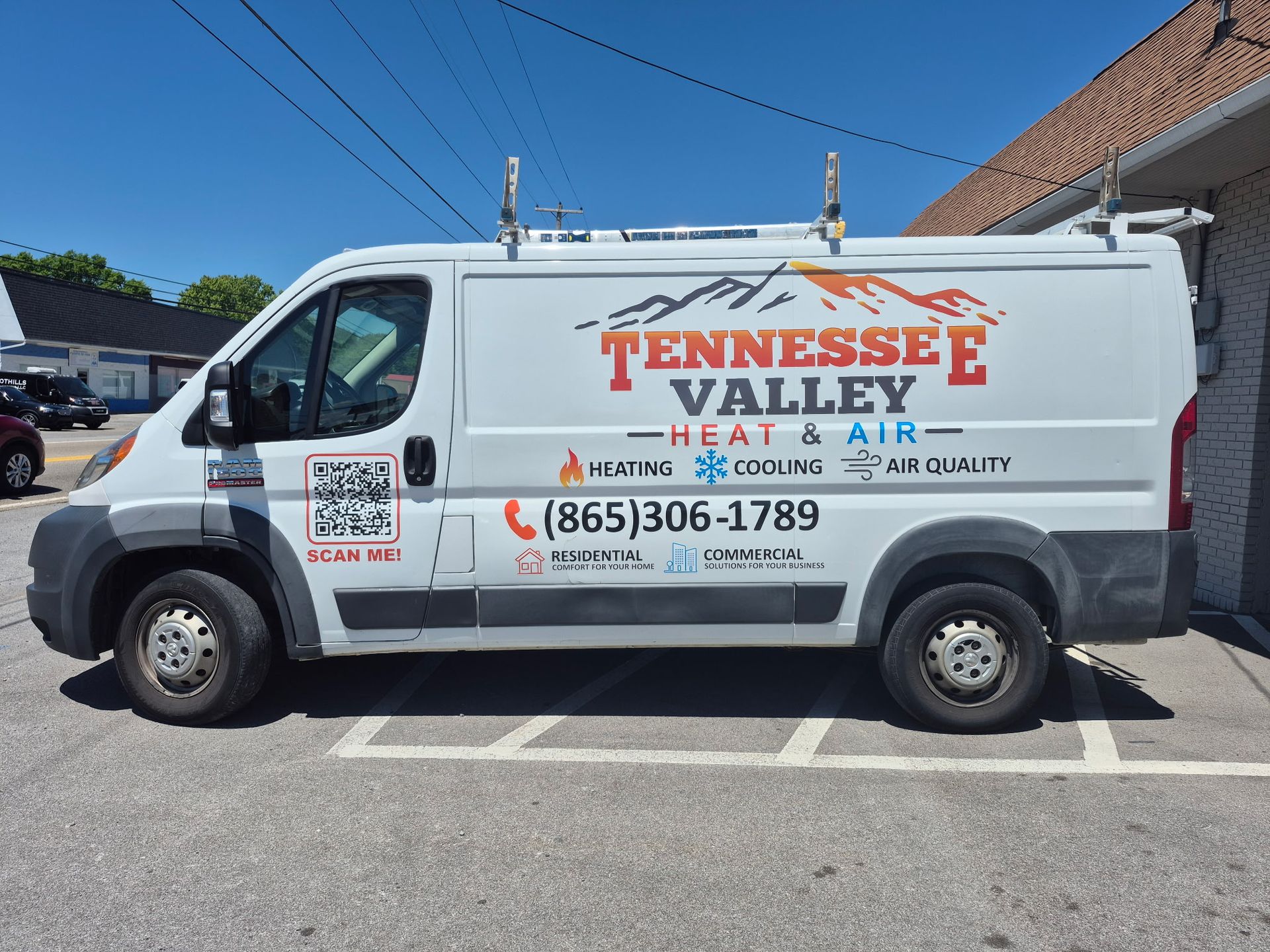 White Tennessee Valley plumbing service van parked outdoors in a lot, with red company branding and phone number.