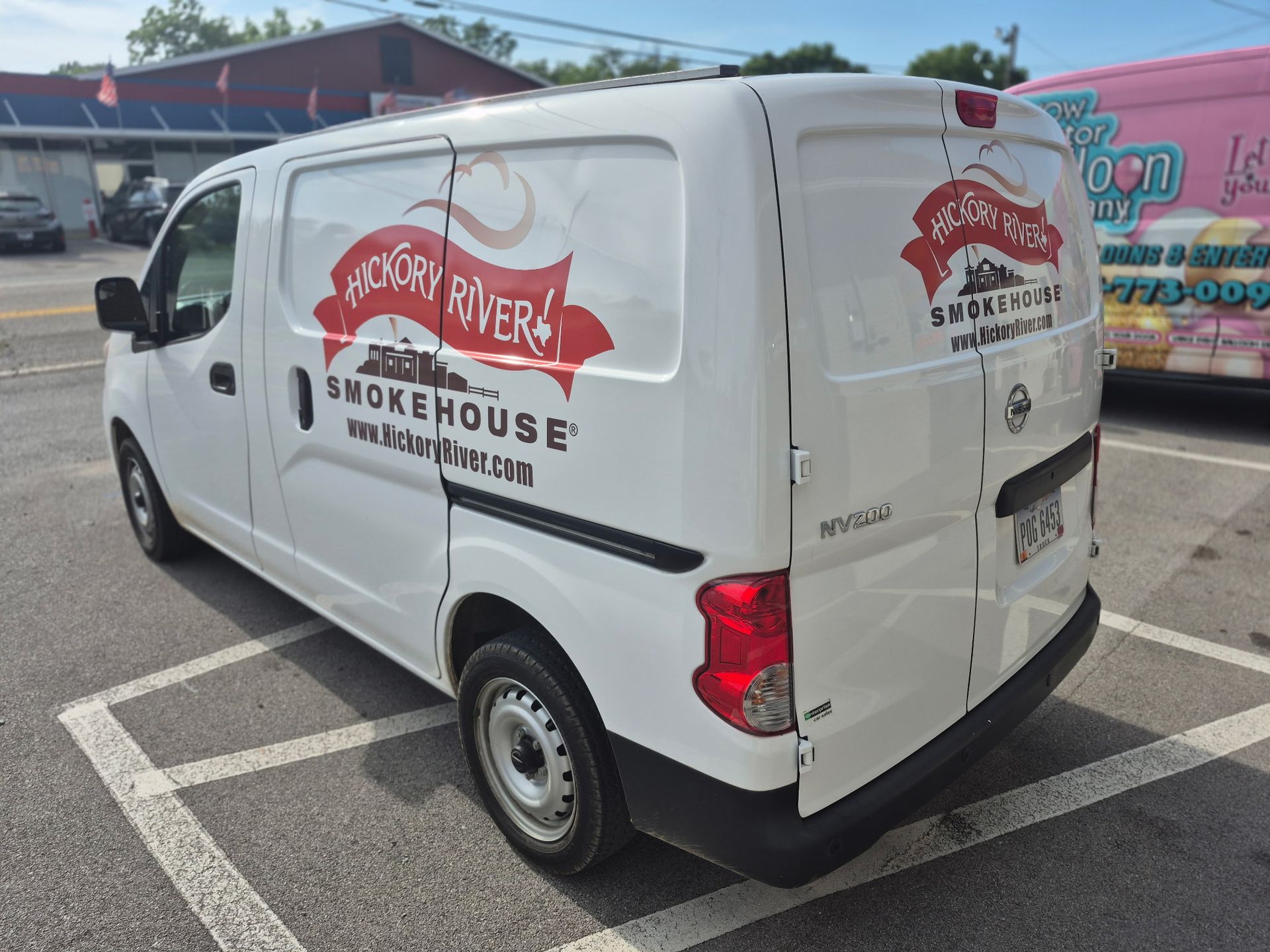 White smokehouse delivery van with red logo parked in a lot on a sunny day