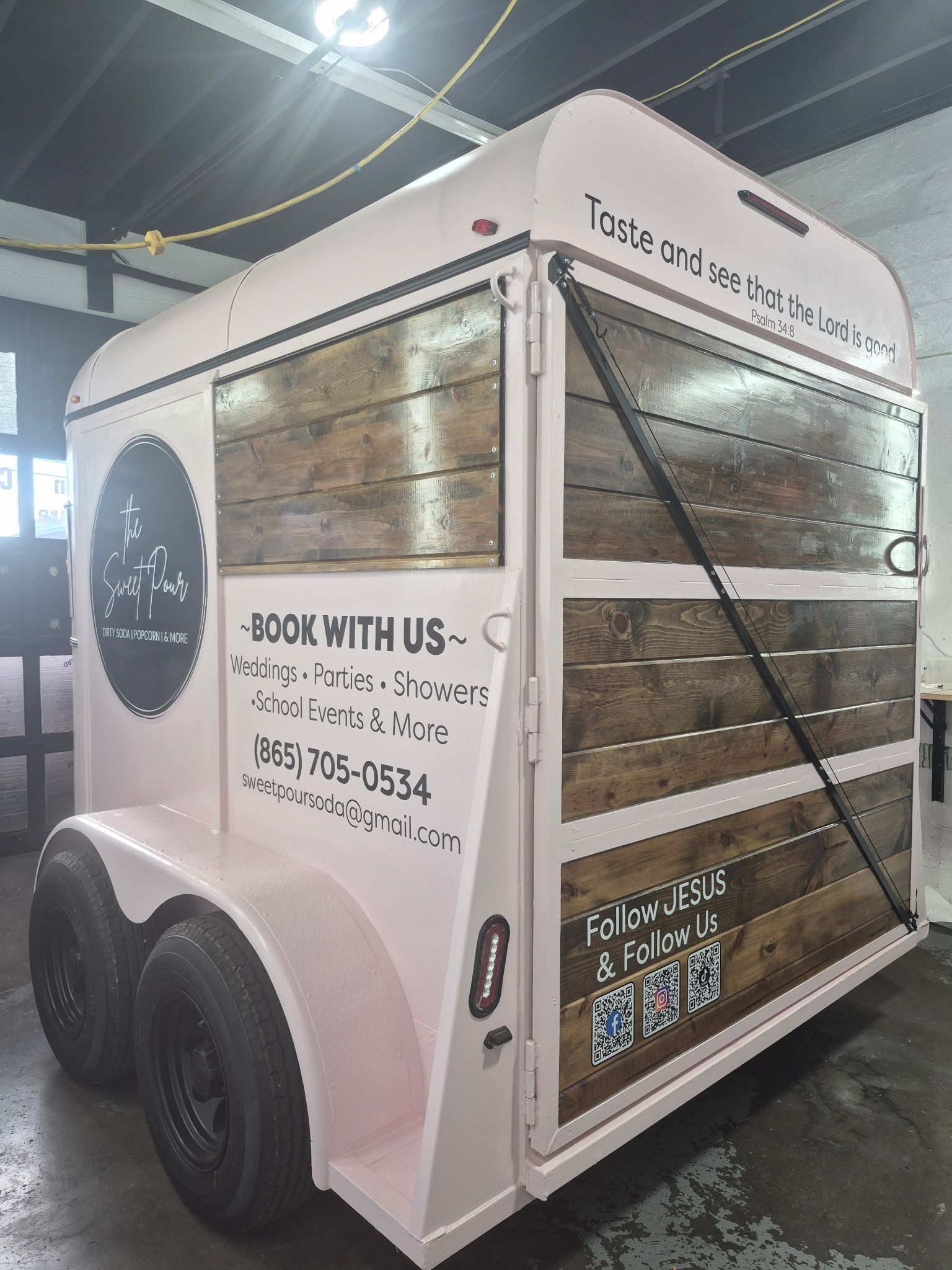 White advertising trailer with a QR code and black graphics parked indoors under bright lights