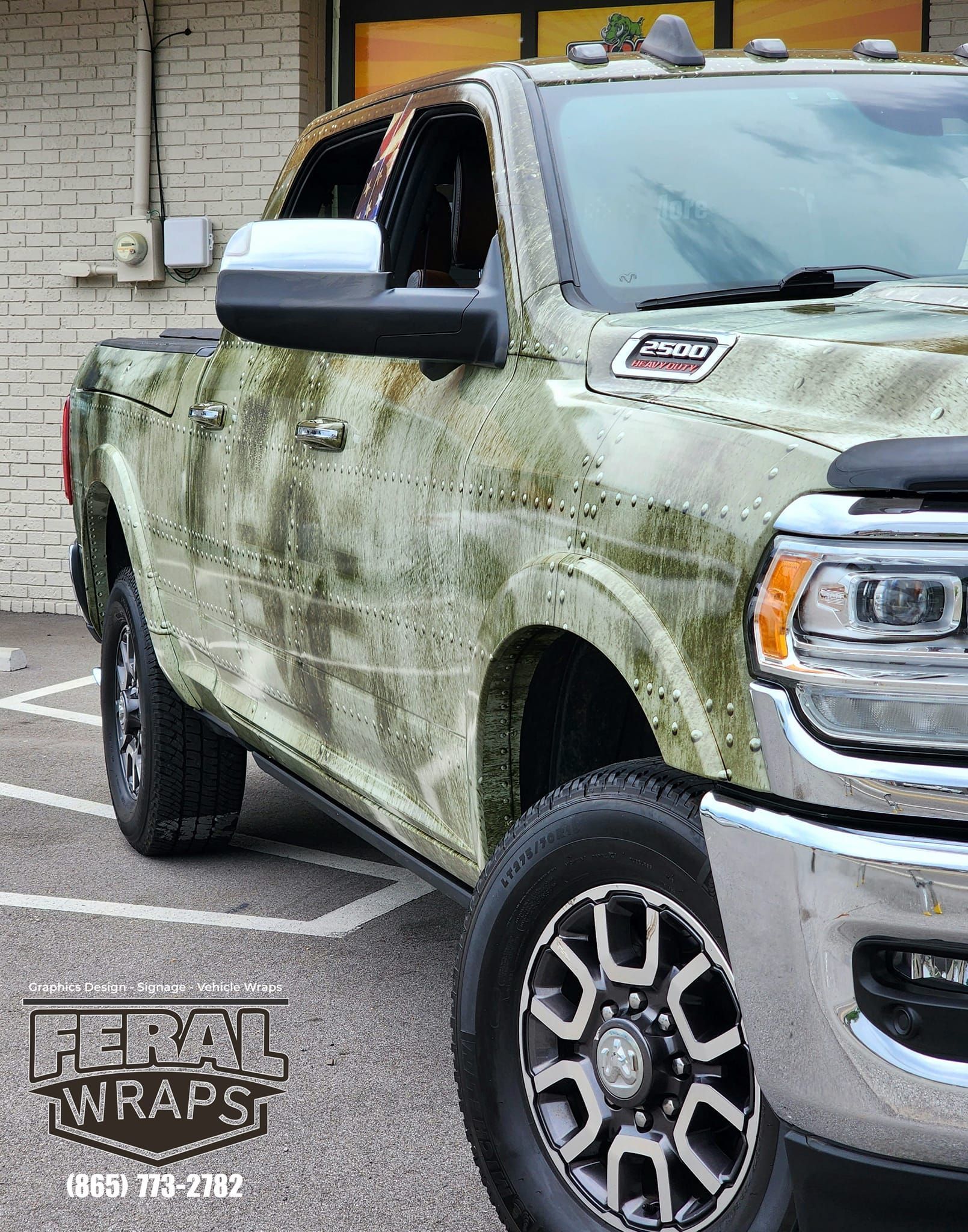 A truck with a camouflage wrap is parked in a parking lot.