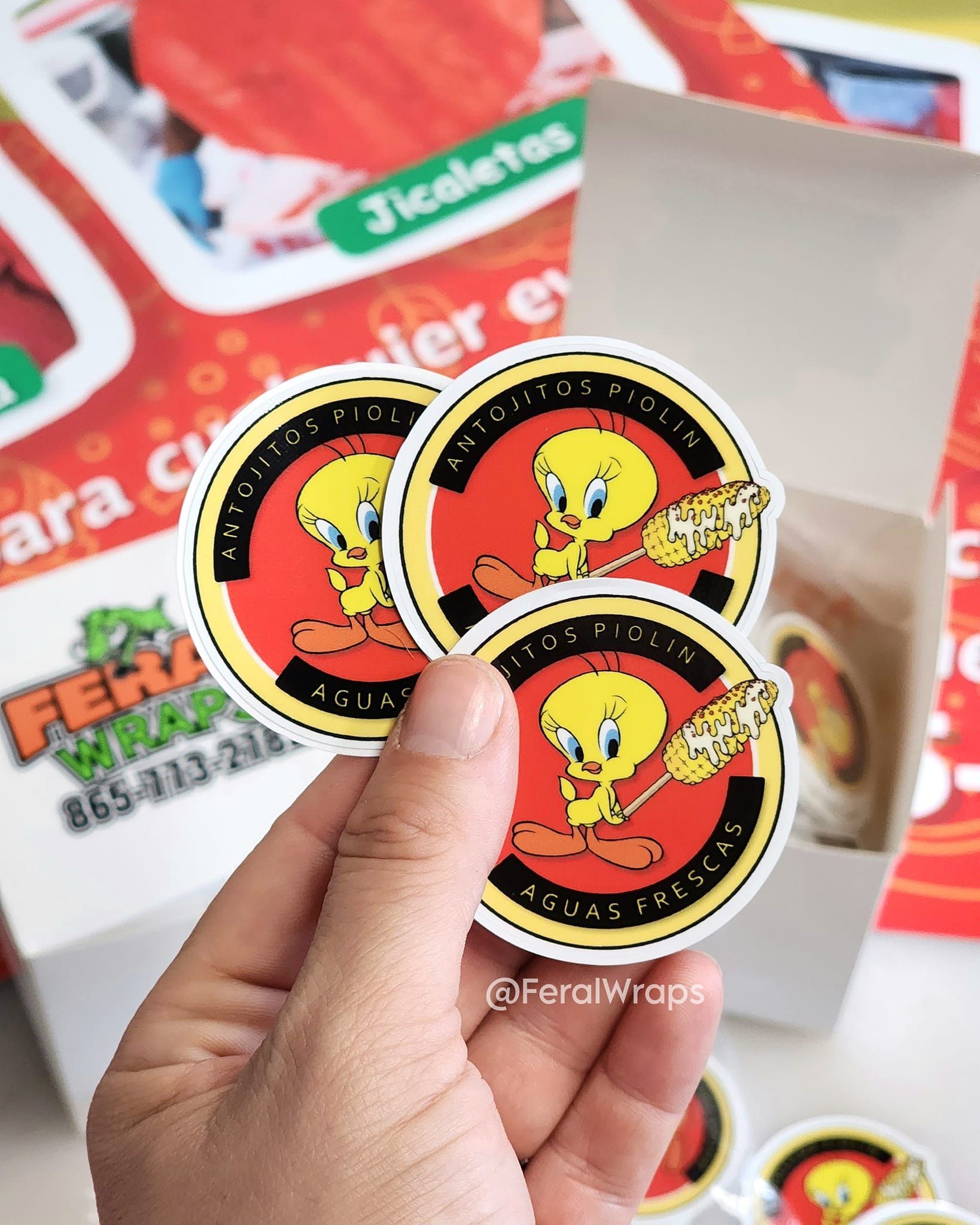 A person is holding three tweety stickers in their hand