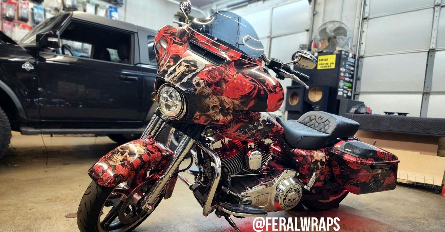 A red motorcycle is parked in a garage next to a black car.