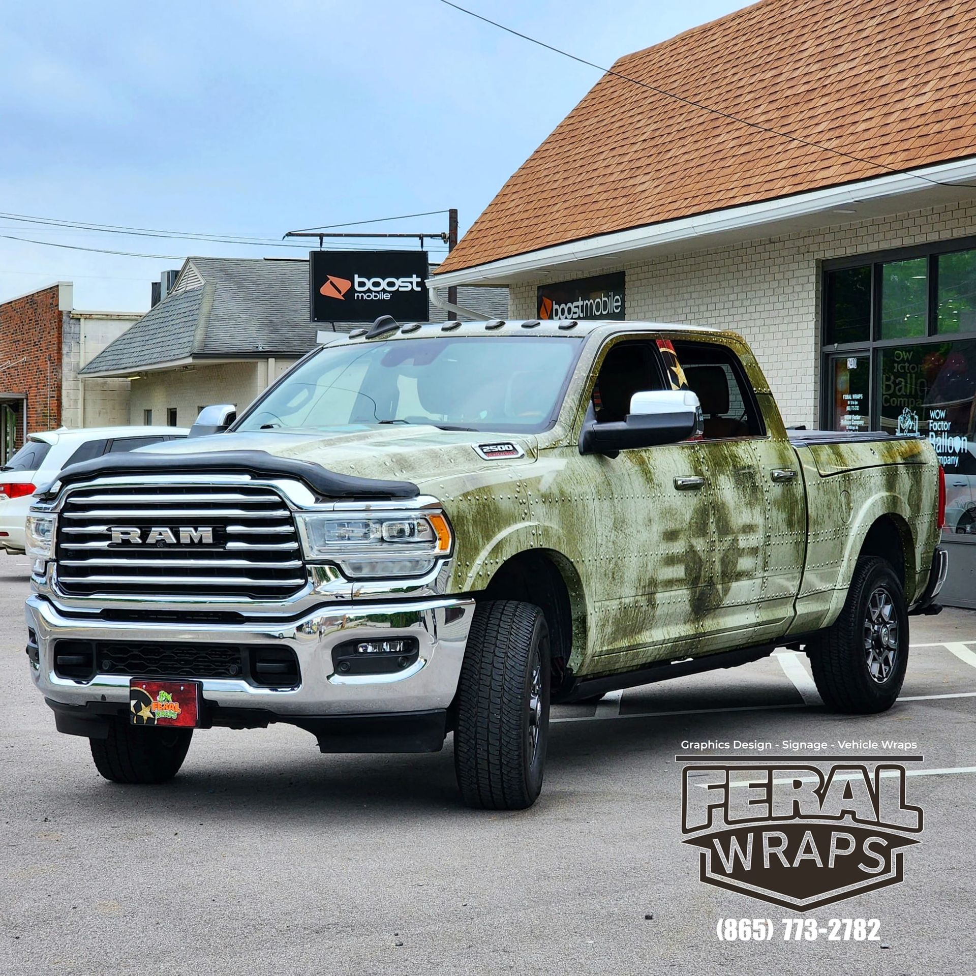 A ram truck with a camouflage paint job is parked in front of a building