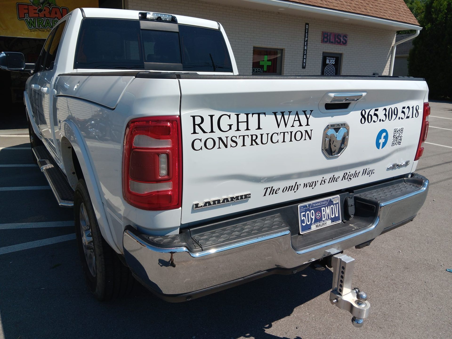 A white truck is parked in front of a building that says right way construction