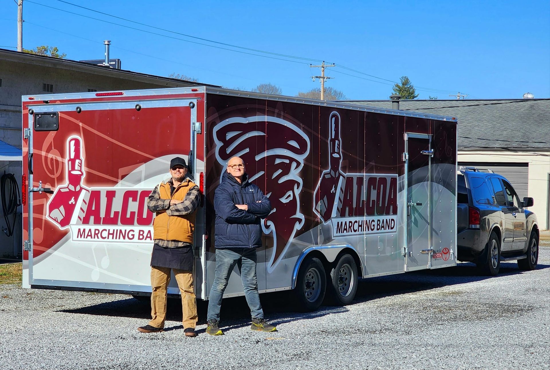Two men are standing next to a trailer that says falcon on it.