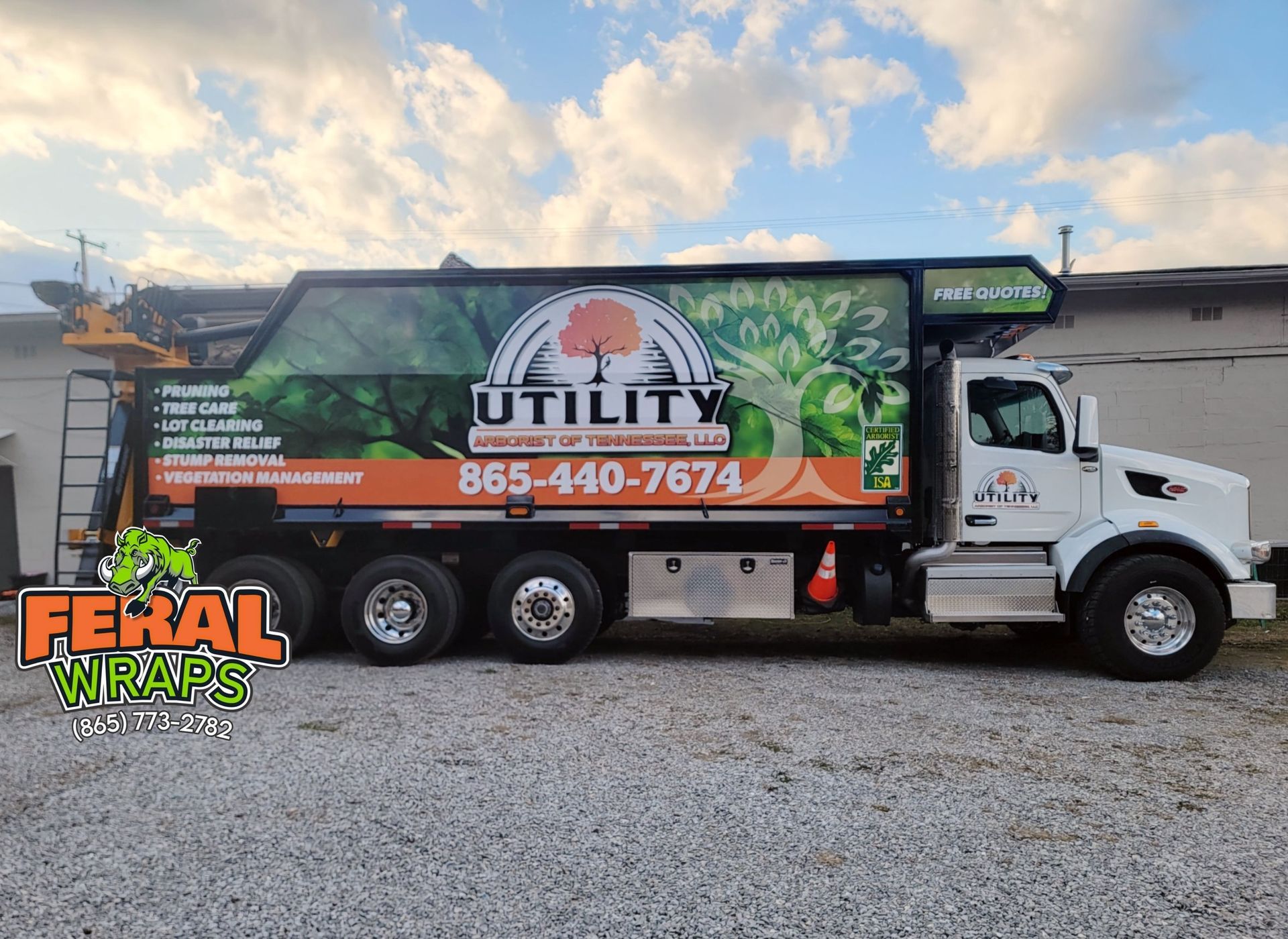 A utility truck is parked in a gravel lot in front of a building.
