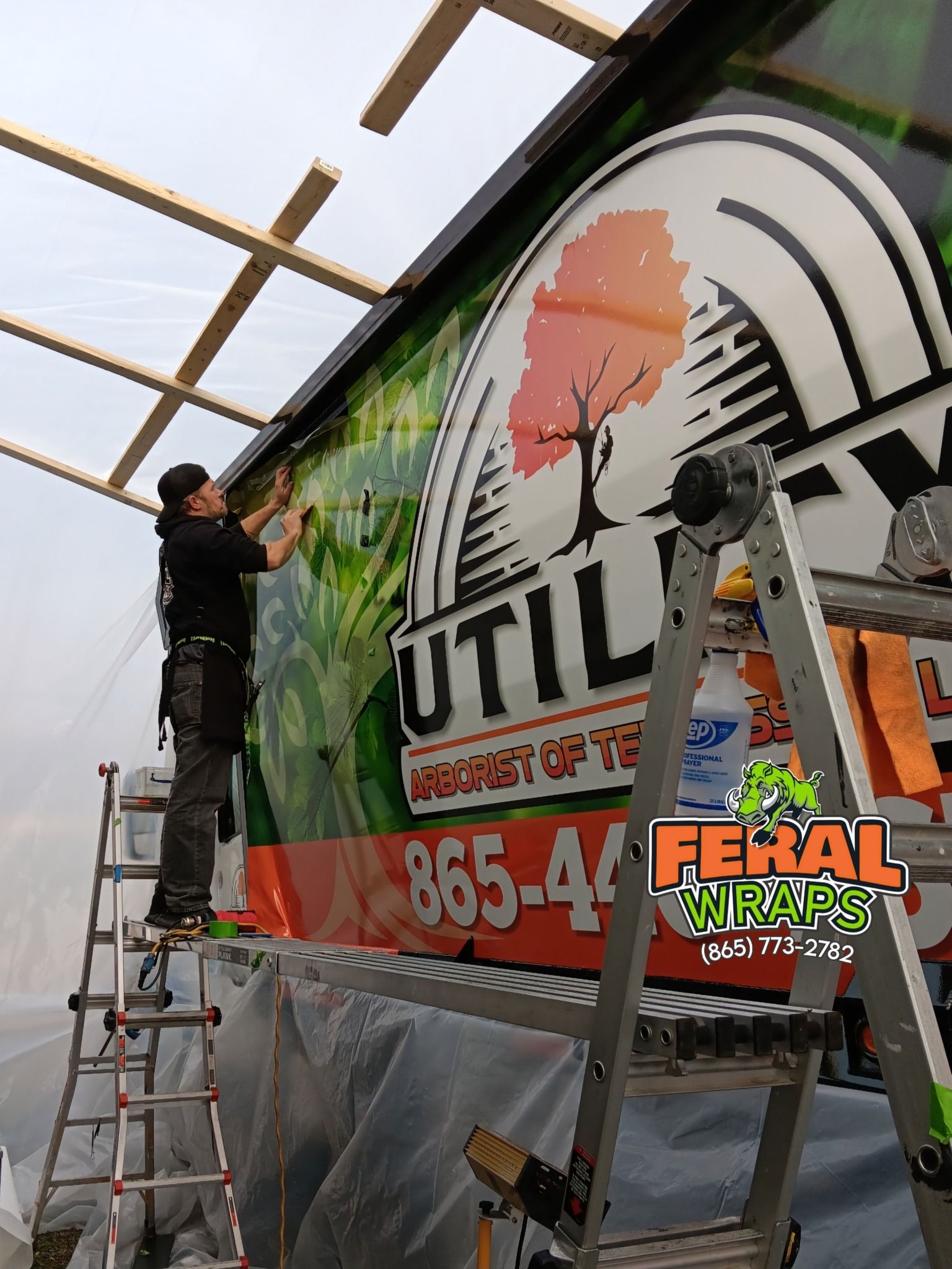 A man on a ladder is working on a sign that says utility