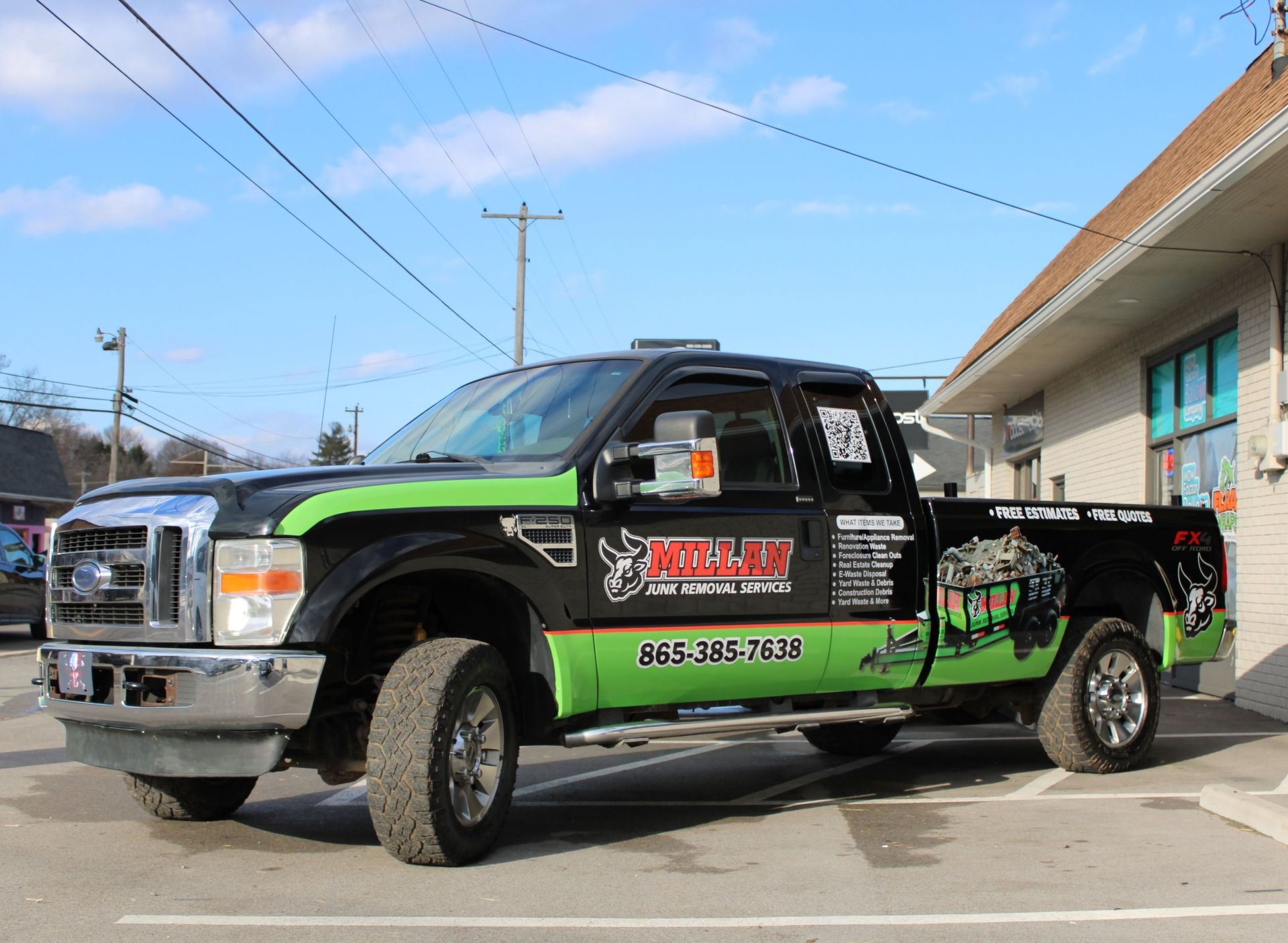 A black and green truck is parked in front of a building.